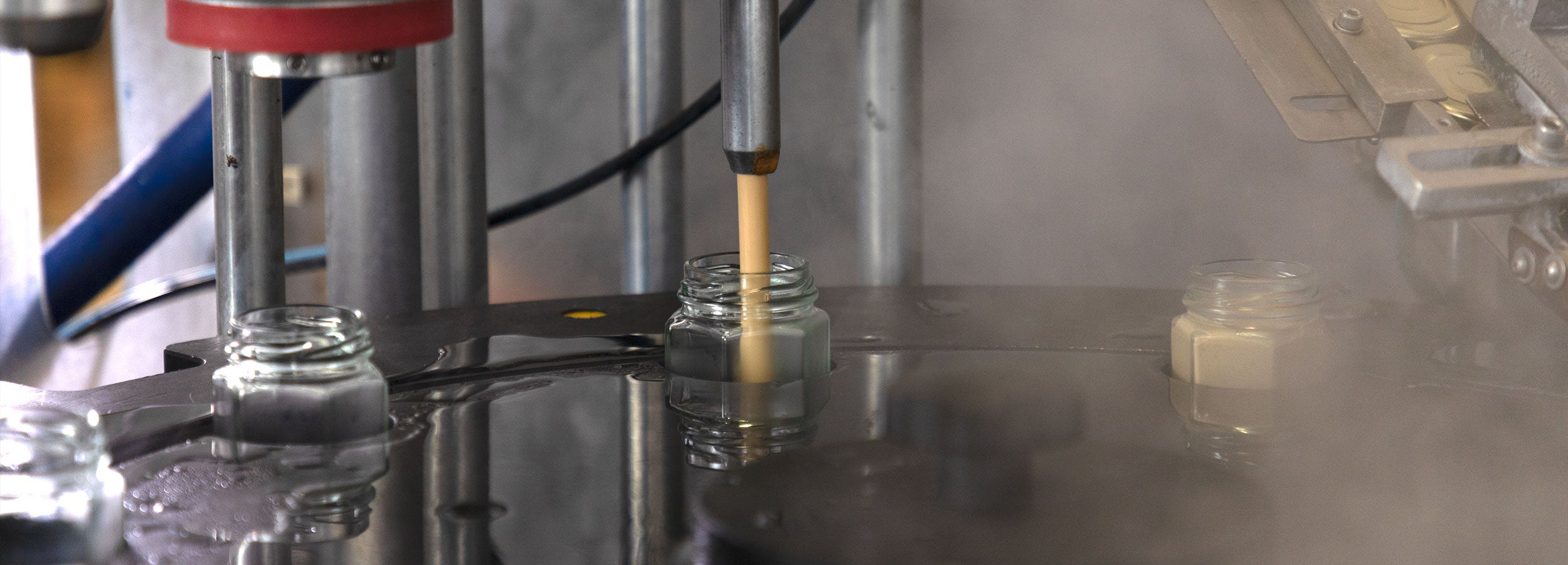 a liquid being poured into a glass jar