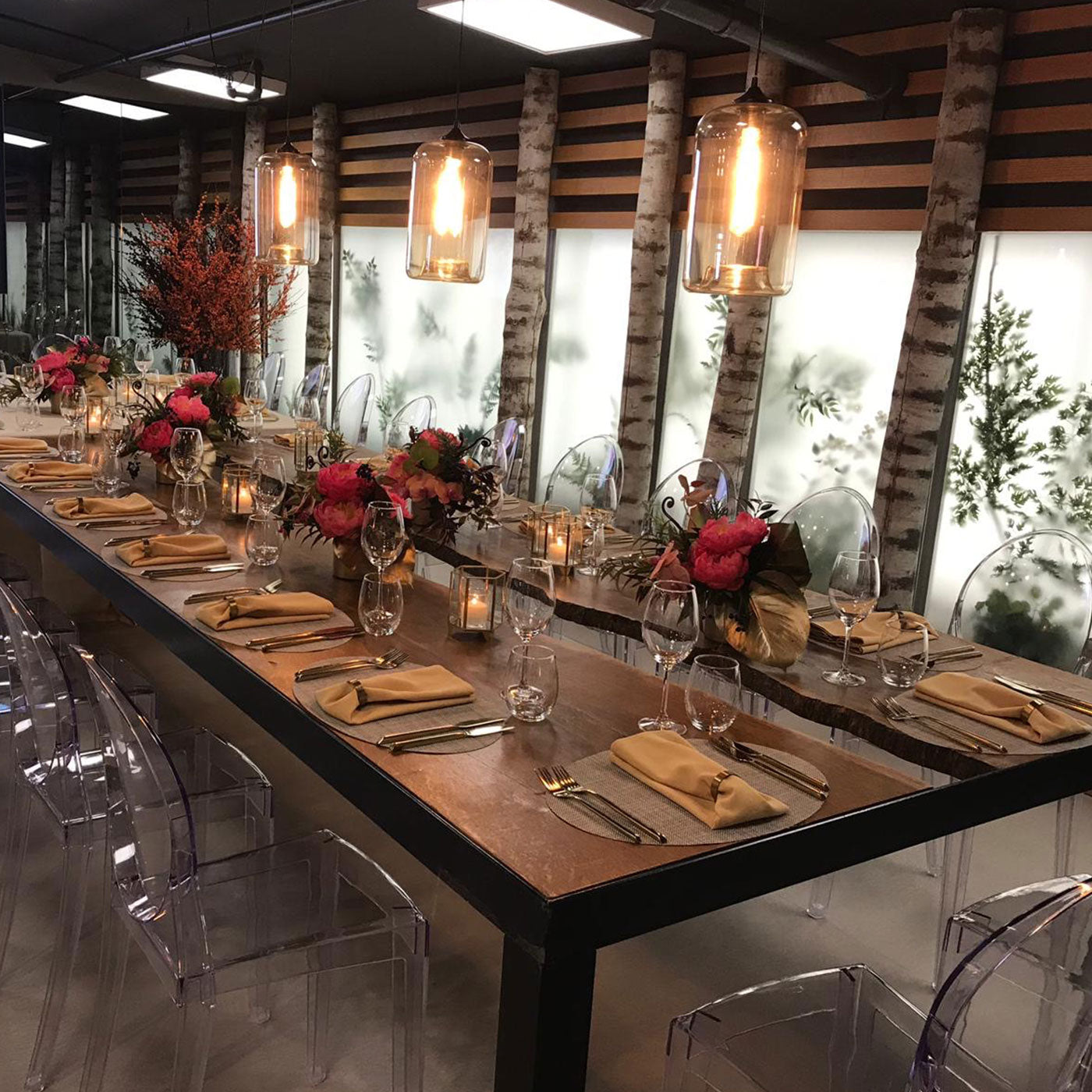 a long table with clear chairs and flowers