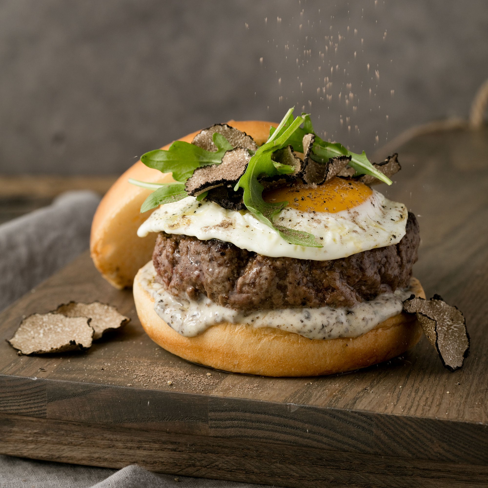 a burger with a fried egg and lettuce on a wooden board
