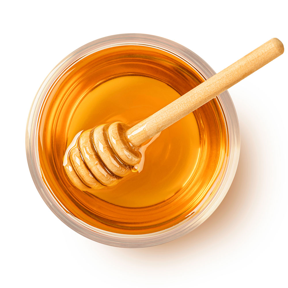 a glass of honey with a wooden stick