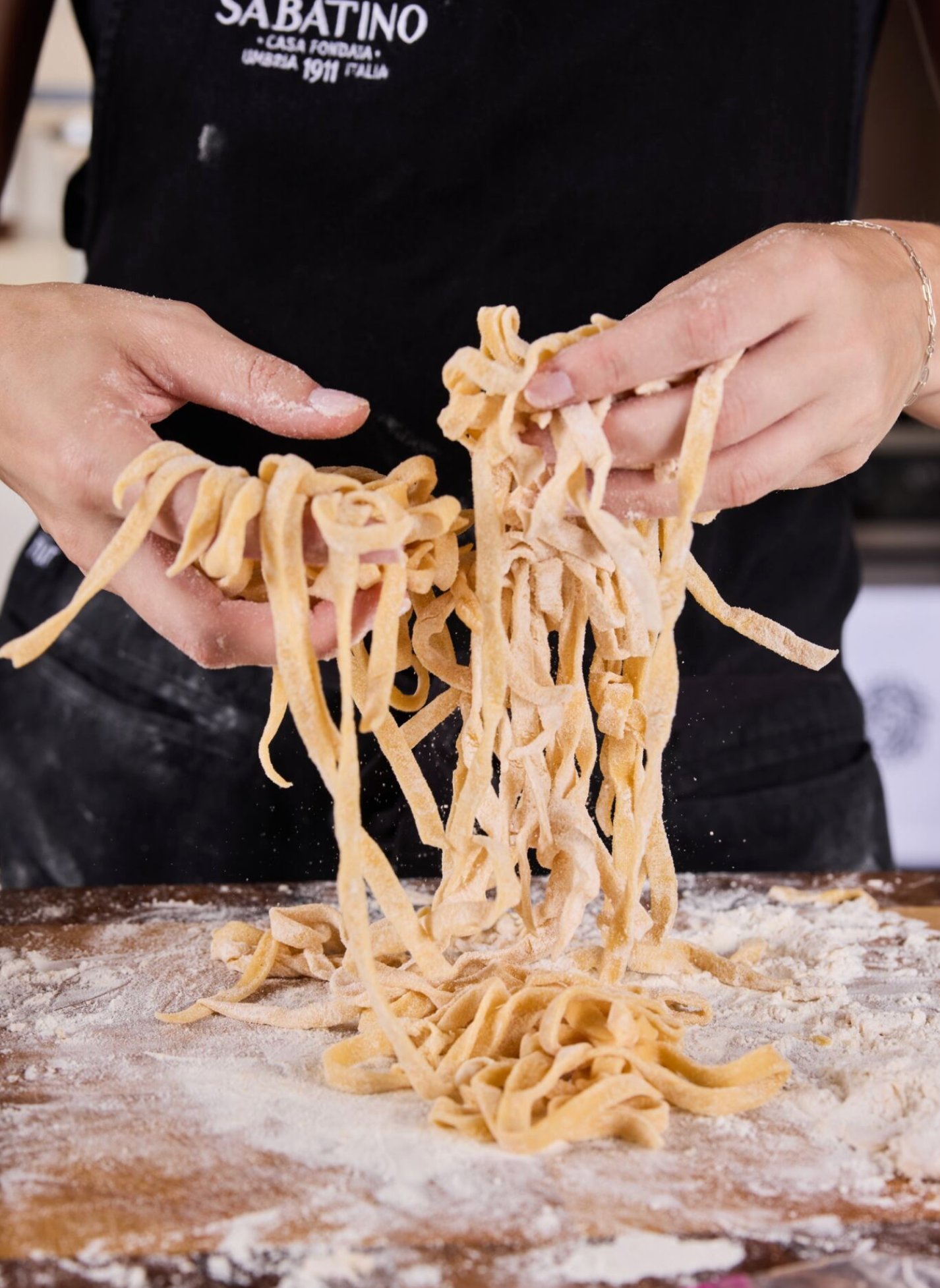 a person holding pasta over flour